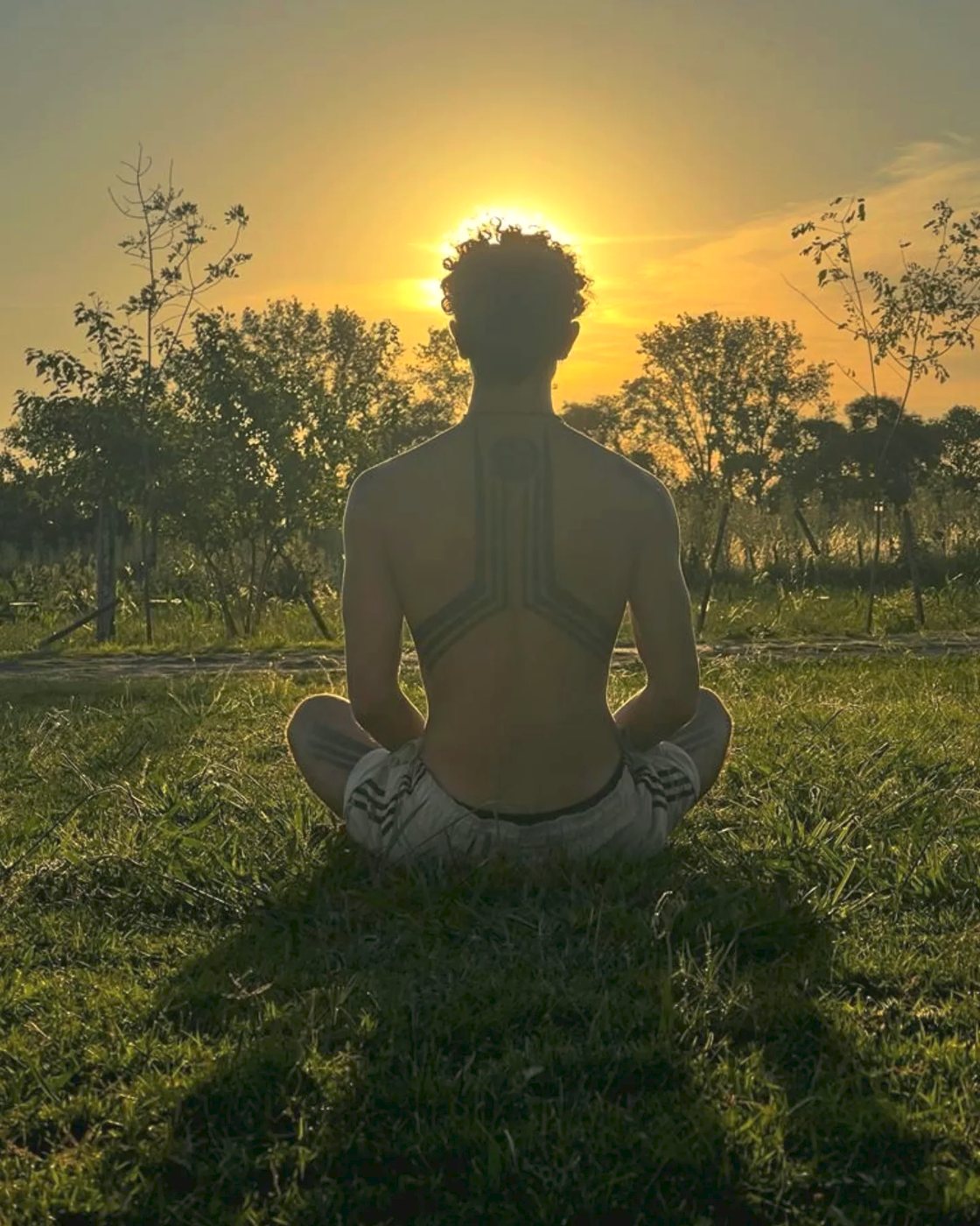 Santi meditando en el pasto al atardecer
